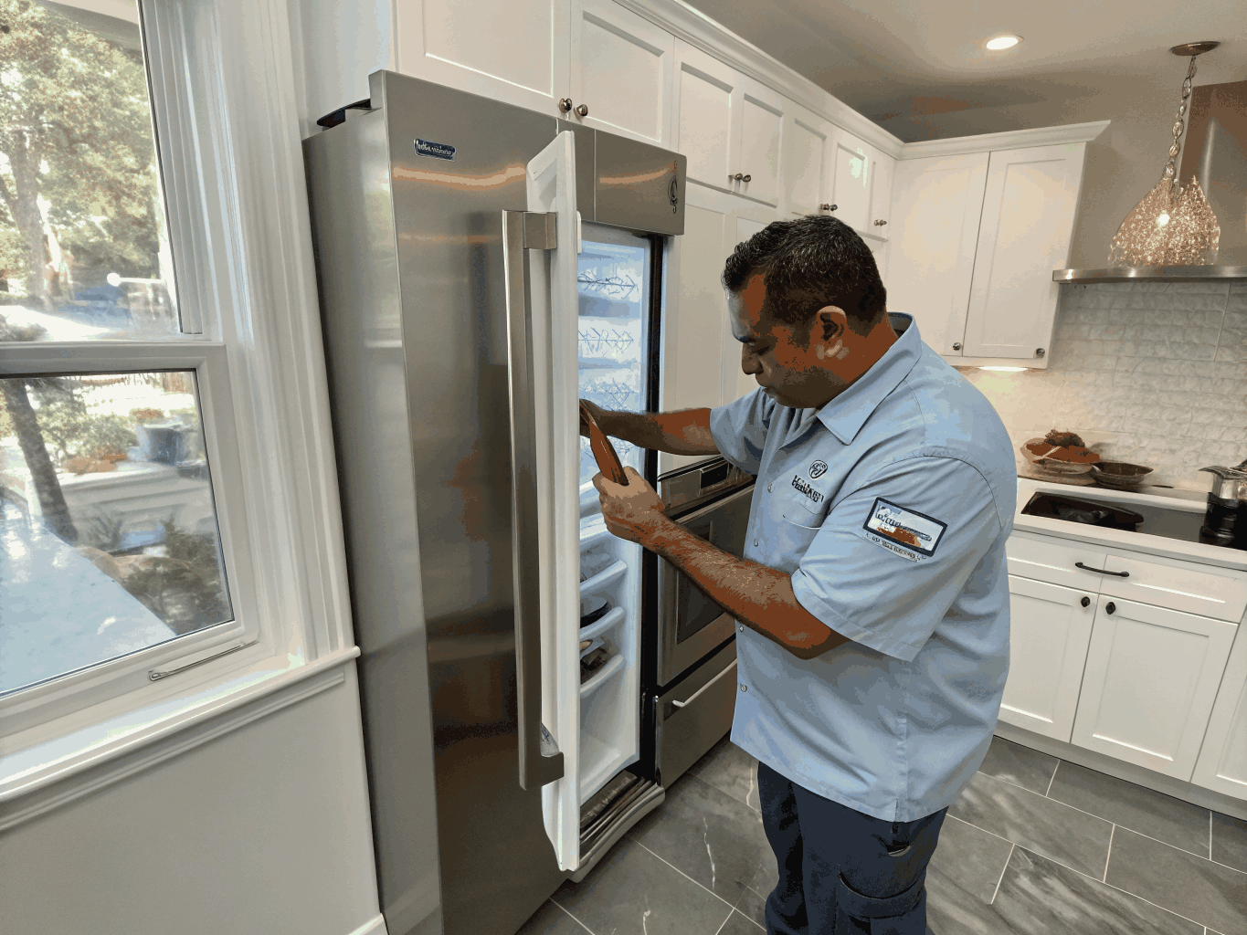 Technician repairing a modern Samsung stainless steel refrigerator and kitchen appliances